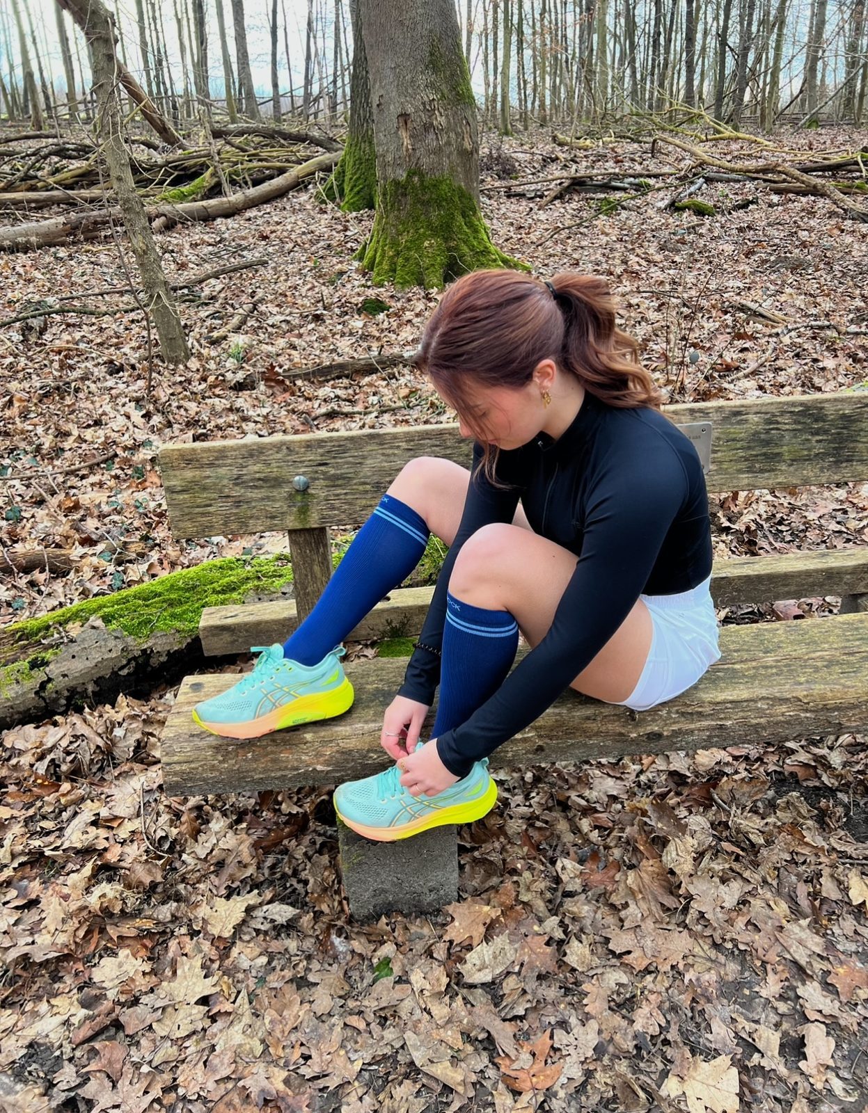 Een vrouw strikt haar schoenen met blauwe Osock compressiesokken aan